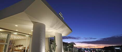 Um hotel com design arquitetônico moderno, com colunas imponentes e entrada destacada.