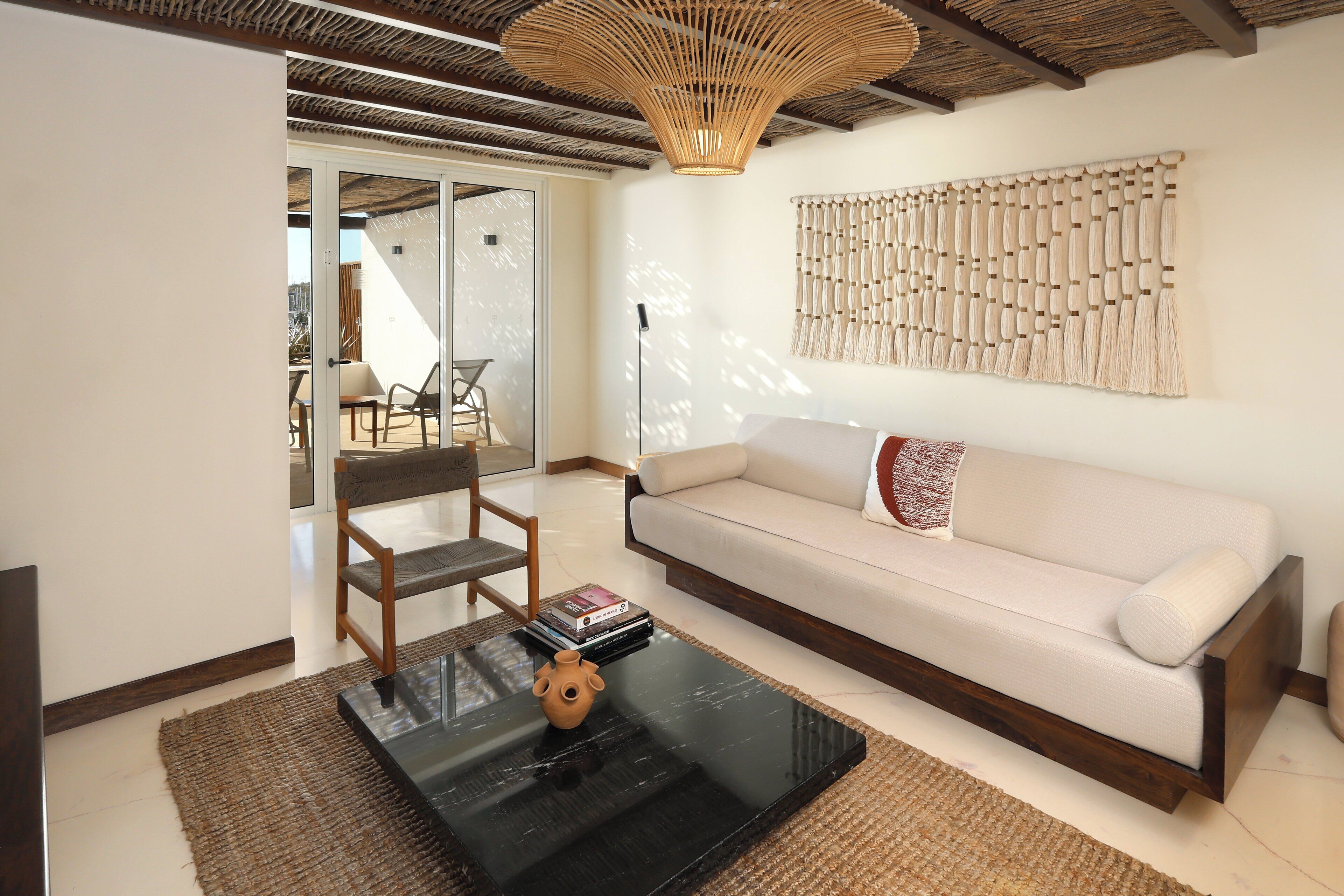 A living room with a sofa, a coffee table, a chair, and a wall-mounted macrame piece.