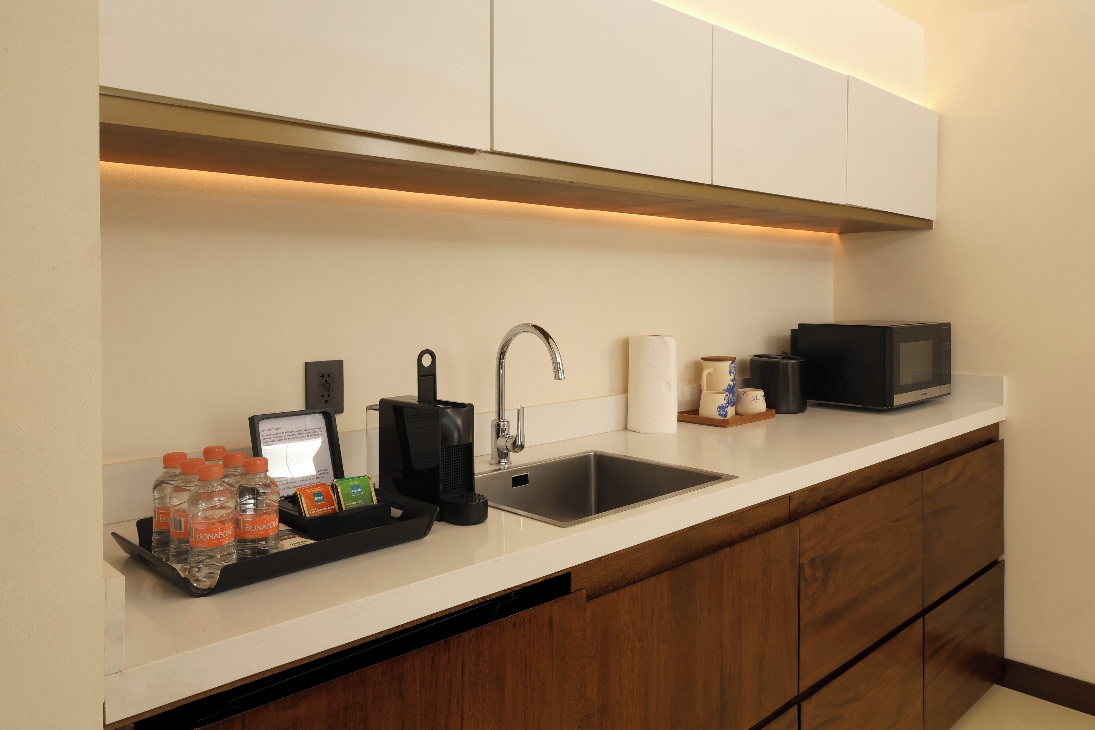 A modern kitchen with a stainless steel sink, a microwave, and a coffee maker.