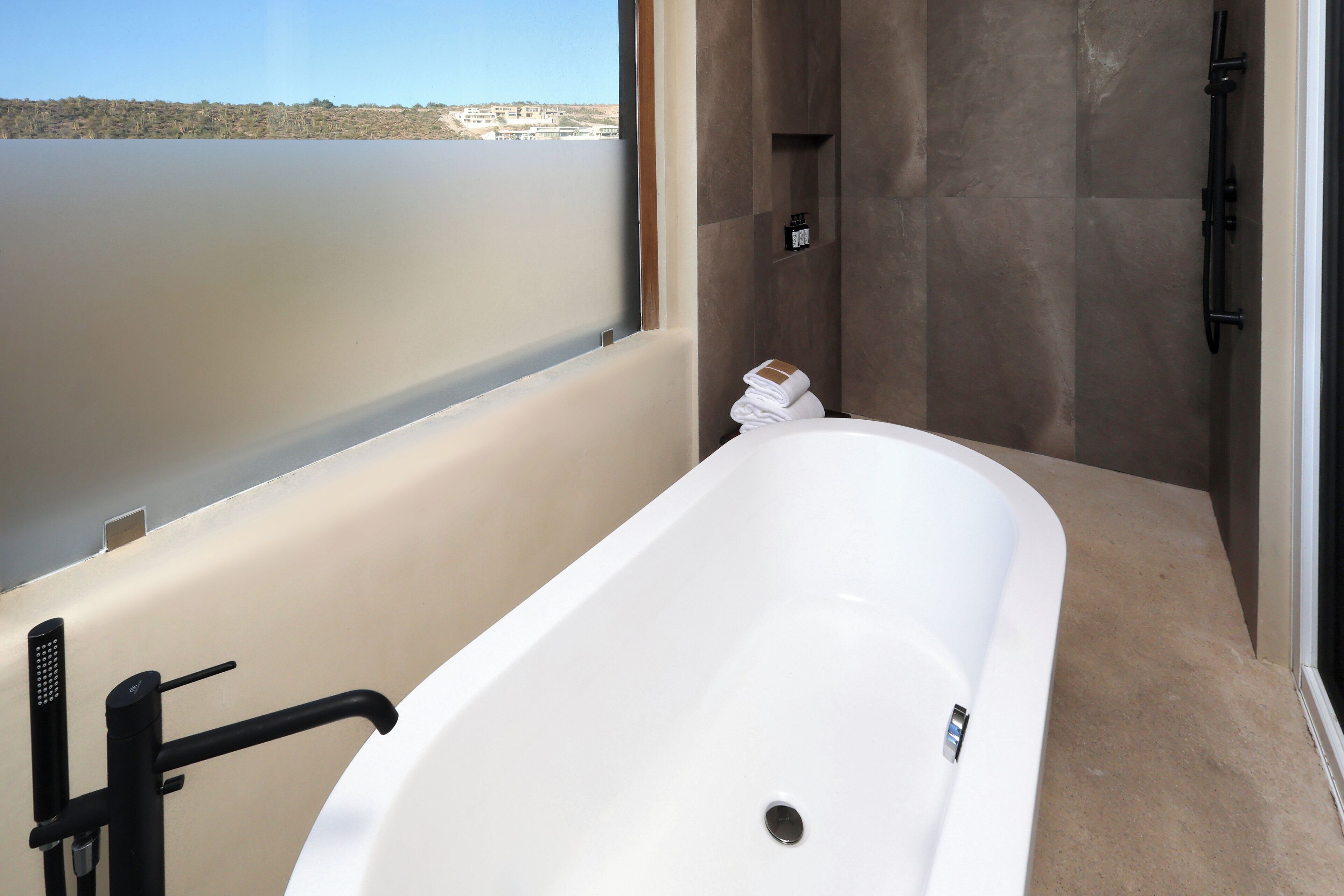 Une salle de bain moderne avec une baignoire, une douche et une vue sur un plan d’eau.