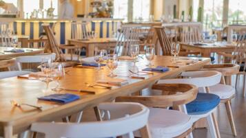 Un restaurante con largas mesas de madera y sillas con cojines blancos y azules.
