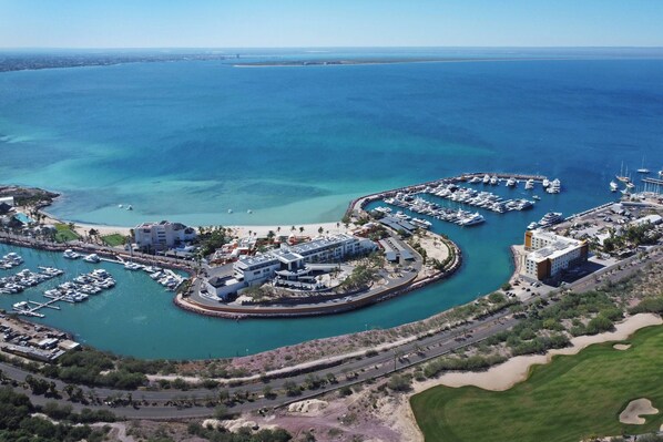 Vista aérea de un puerto deportivo con barcos, una playa y edificios.