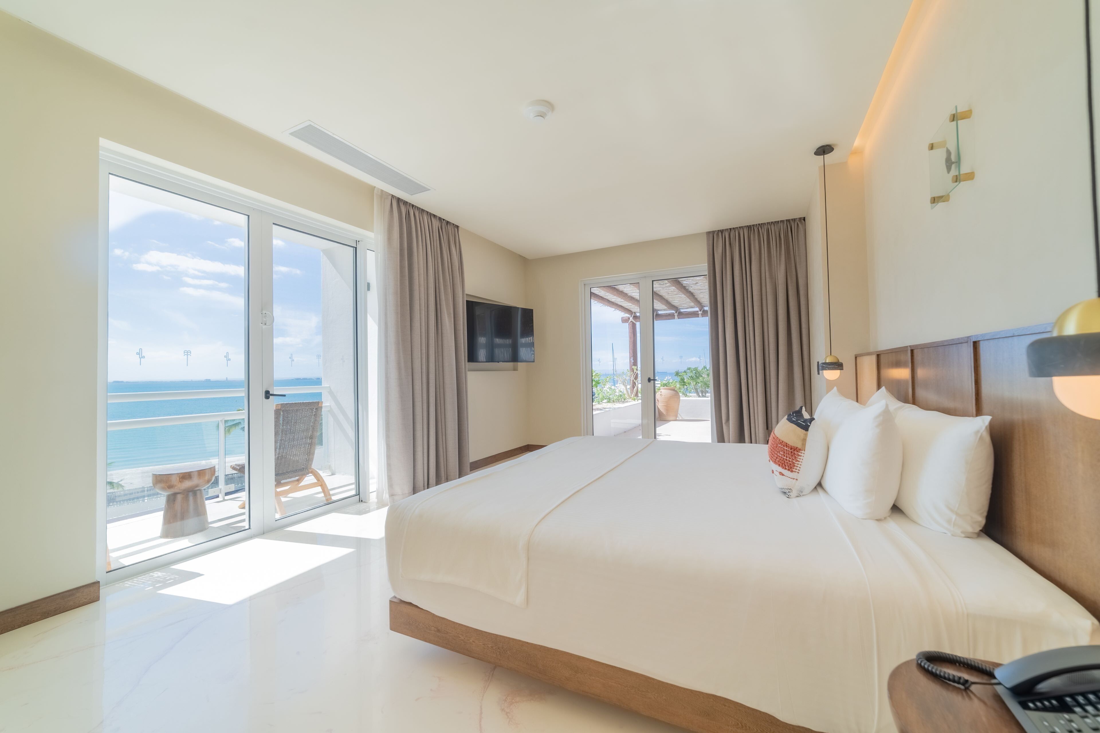 Een hotelkamer met een groot bed, een televisie en uitzicht op zee.