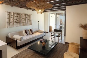 A modern living room with a sofa, coffee table, and a hanging light fixture.