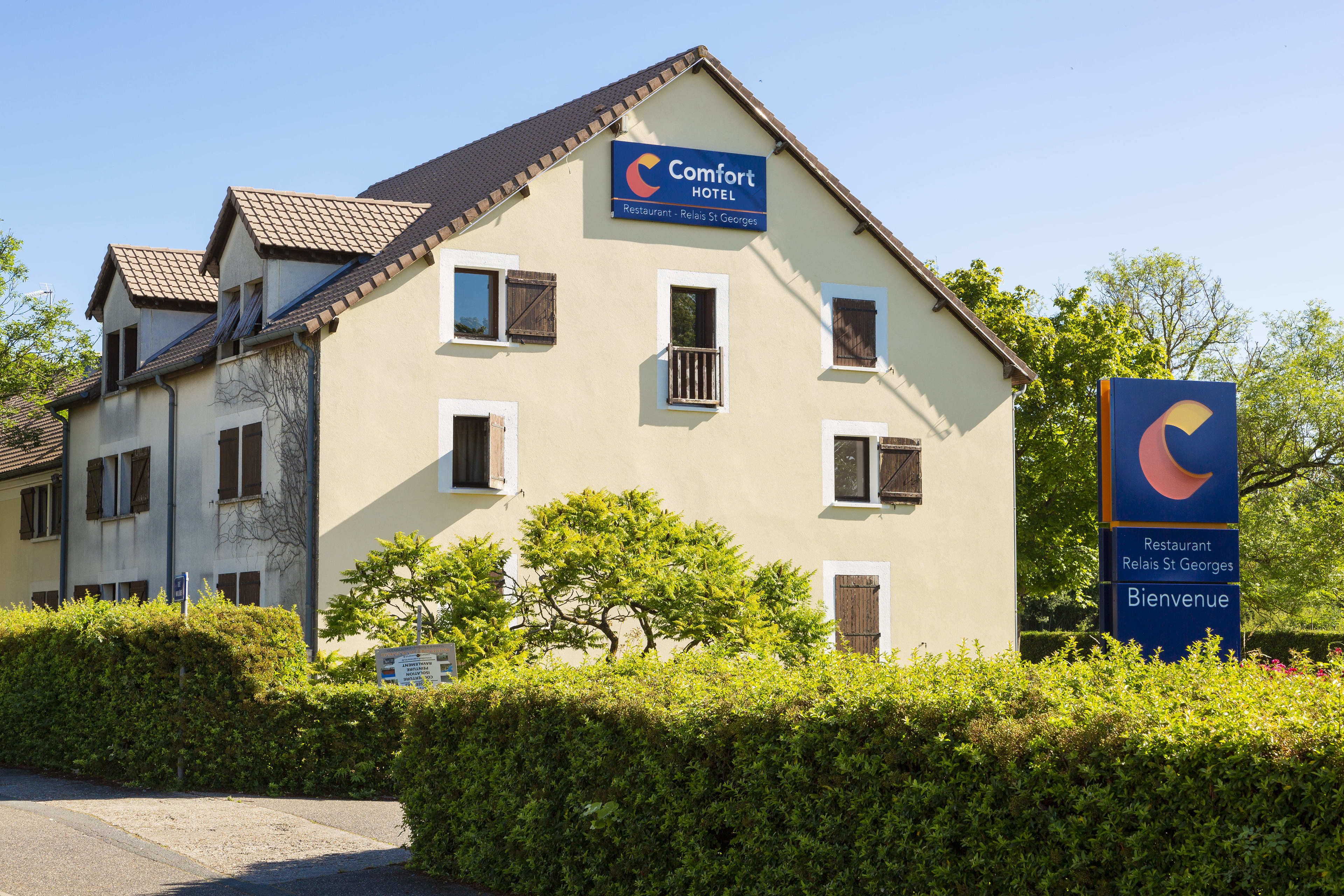 Un edificio de dos pisos con un letrero que indica que es un Comfort Hotel y un restaurante llamado Relais St Georges.