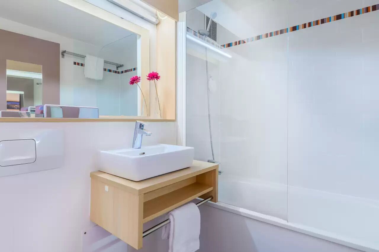 A modern bathroom with a white sink, mirror, and shower.