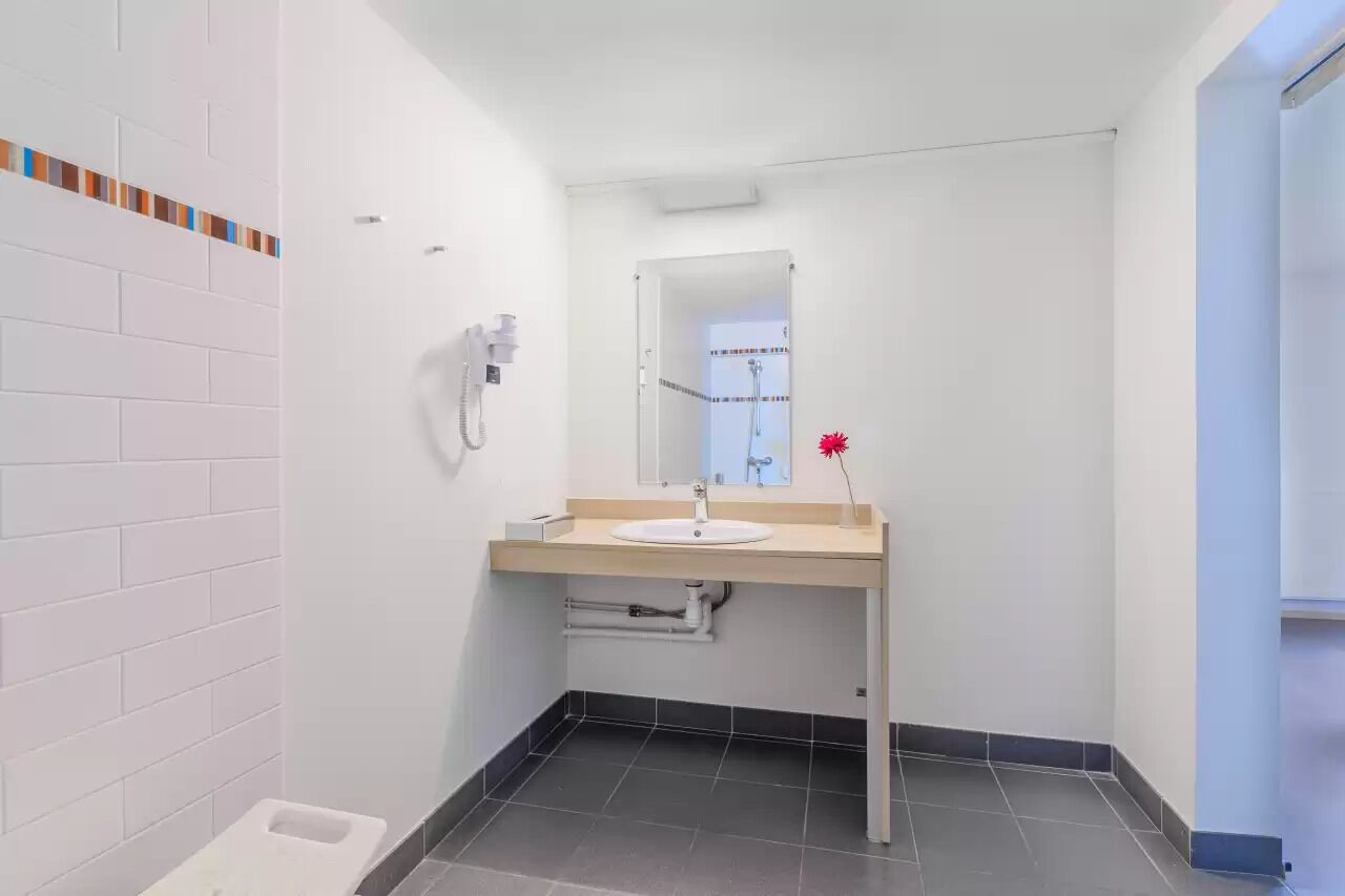 Ein modernes Badezimmer mit Waschbecken, Spiegel und Duschkabine.