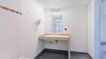 A modern bathroom with a white sink, mirror, and a shower enclosure.