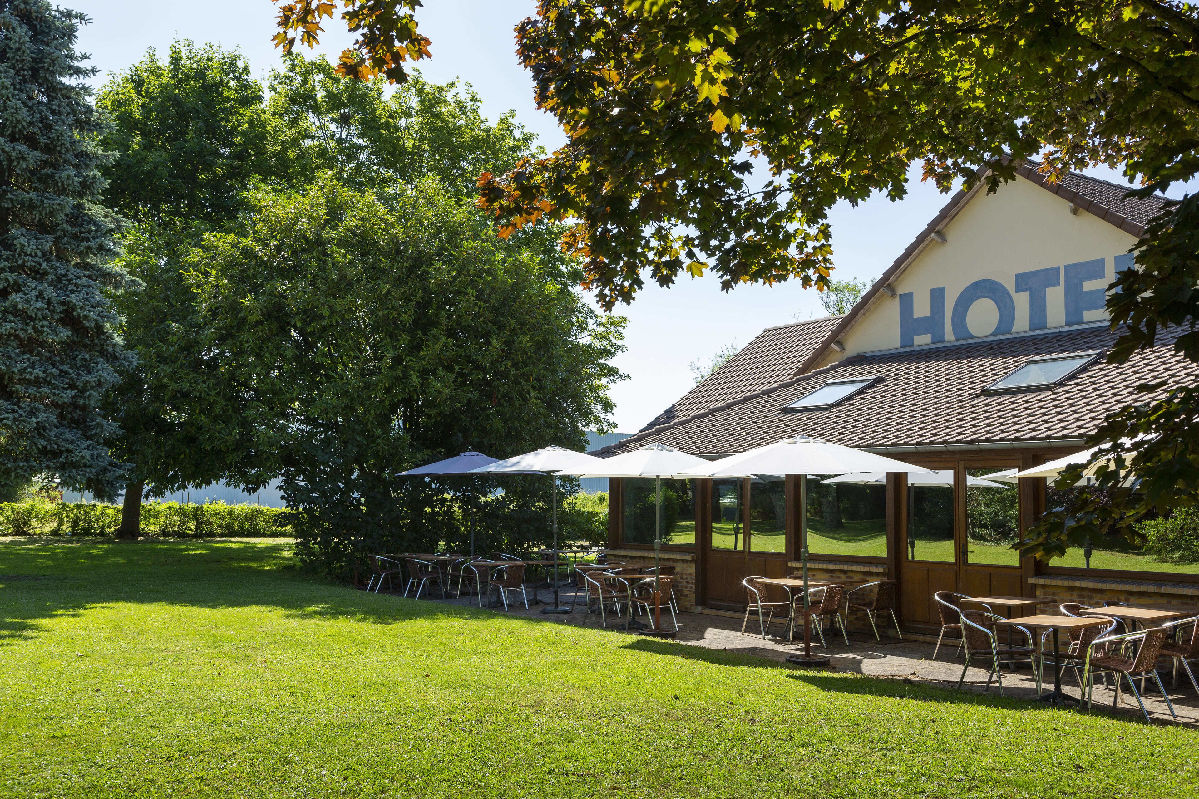 A hotel with outdoor seating and a large sign.