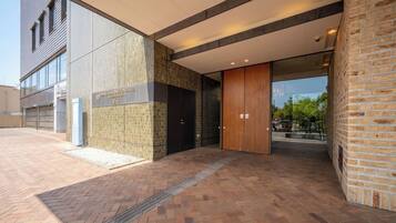 Een modern gebouwde ingang met een bakstenen gevel, een glazen deur en een bord waarop een hotel wordt aangegeven.
