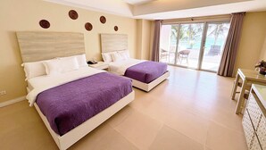 Habitación de hotel con dos camas, un escritorio y vistas al área exterior.