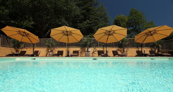 Una piscina al aire libre de temporada, sombrillas