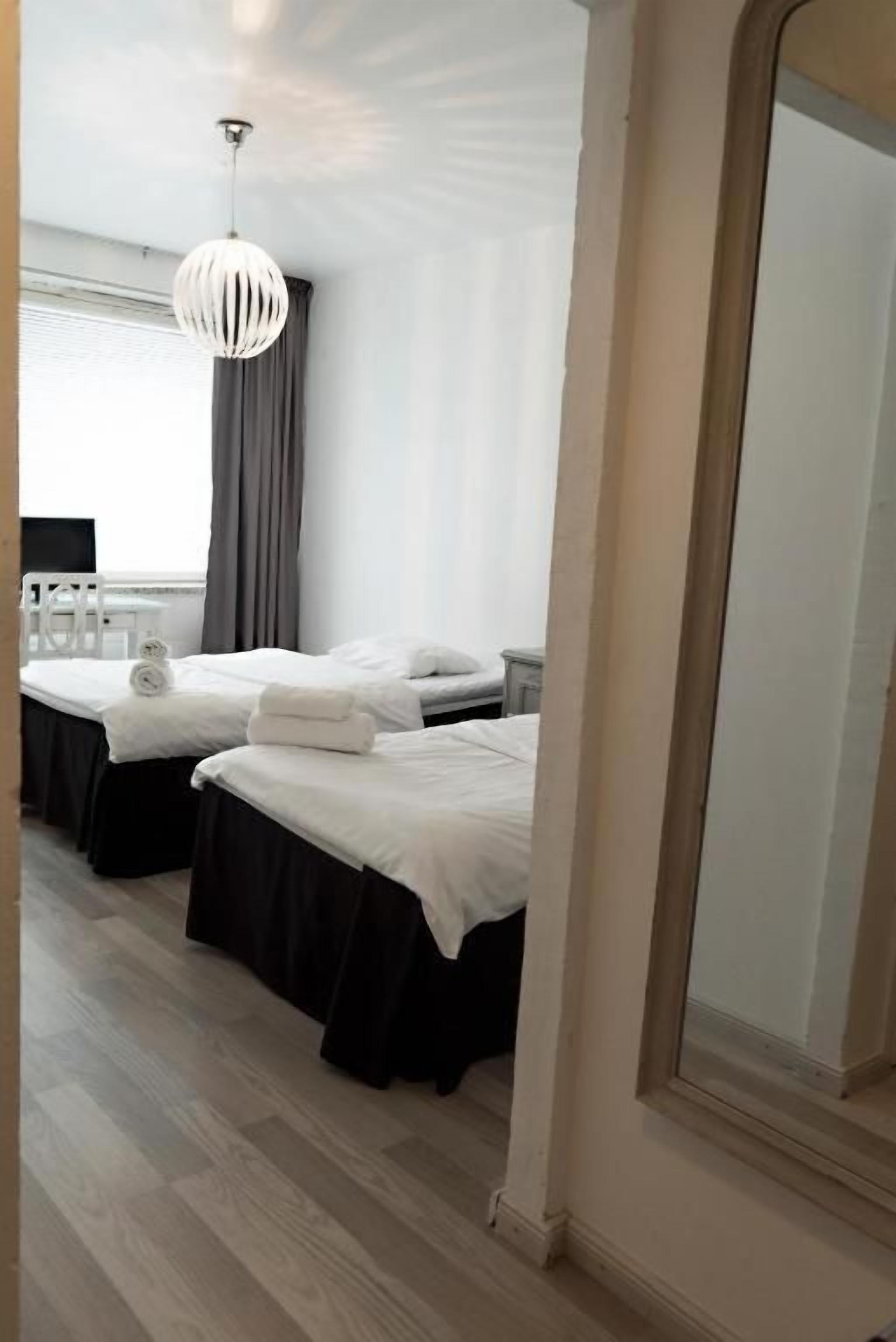 A hotel room with two beds, a large mirror, and a hanging light fixture.
