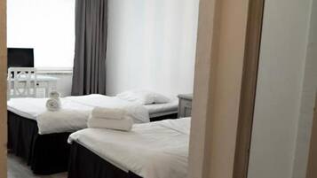 A hotel room with two beds, a large mirror, and a hanging light fixture.