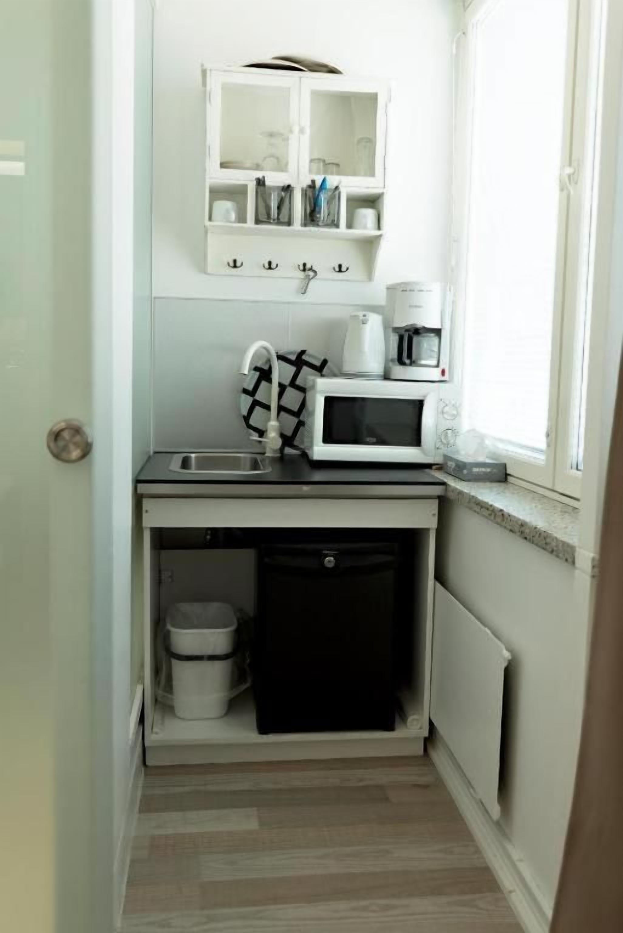 Une cuisine compacte équipée d’un four à micro-ondes, d’une machine à café et d’un petit évier.