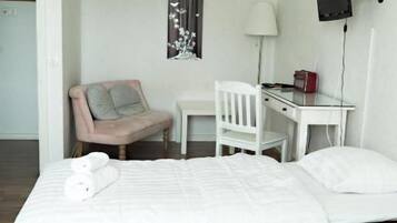 Hotellihuone, jossa on sänky, työpöytä, tuoli, televisio ja ikkuna, jossa on verhot.