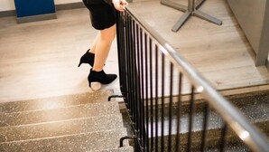 A woman descending a staircase with a railing, a table with informational brochures, and a window in the background. - Hotel Alexander (Maenttae-Vilppula)