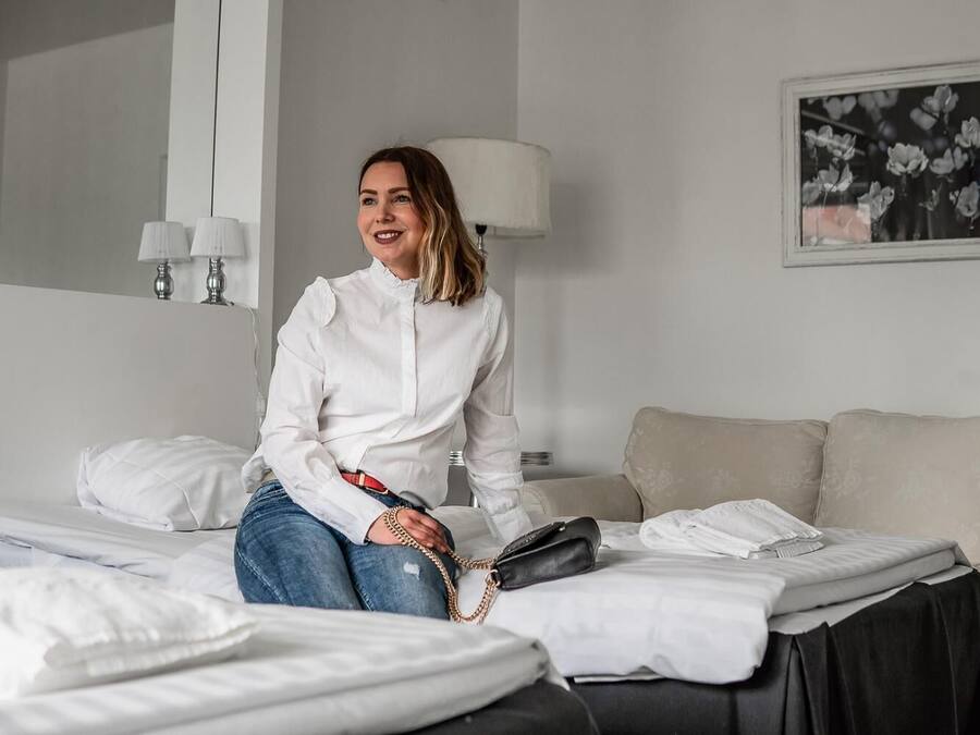 A hotel room with a bed, a sofa, a lamp, and a framed picture on the wall.