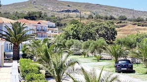 A residential area with houses, palm trees, and a car parked in the driveway. - Panselinos Hotel (Lesvos)