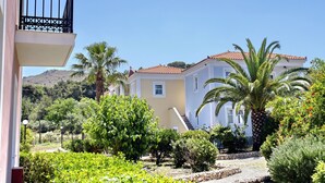 A residential building with a balcony, surrounded by lush greenery and a clear sky. - Panselinos Hotel (Lesvos)