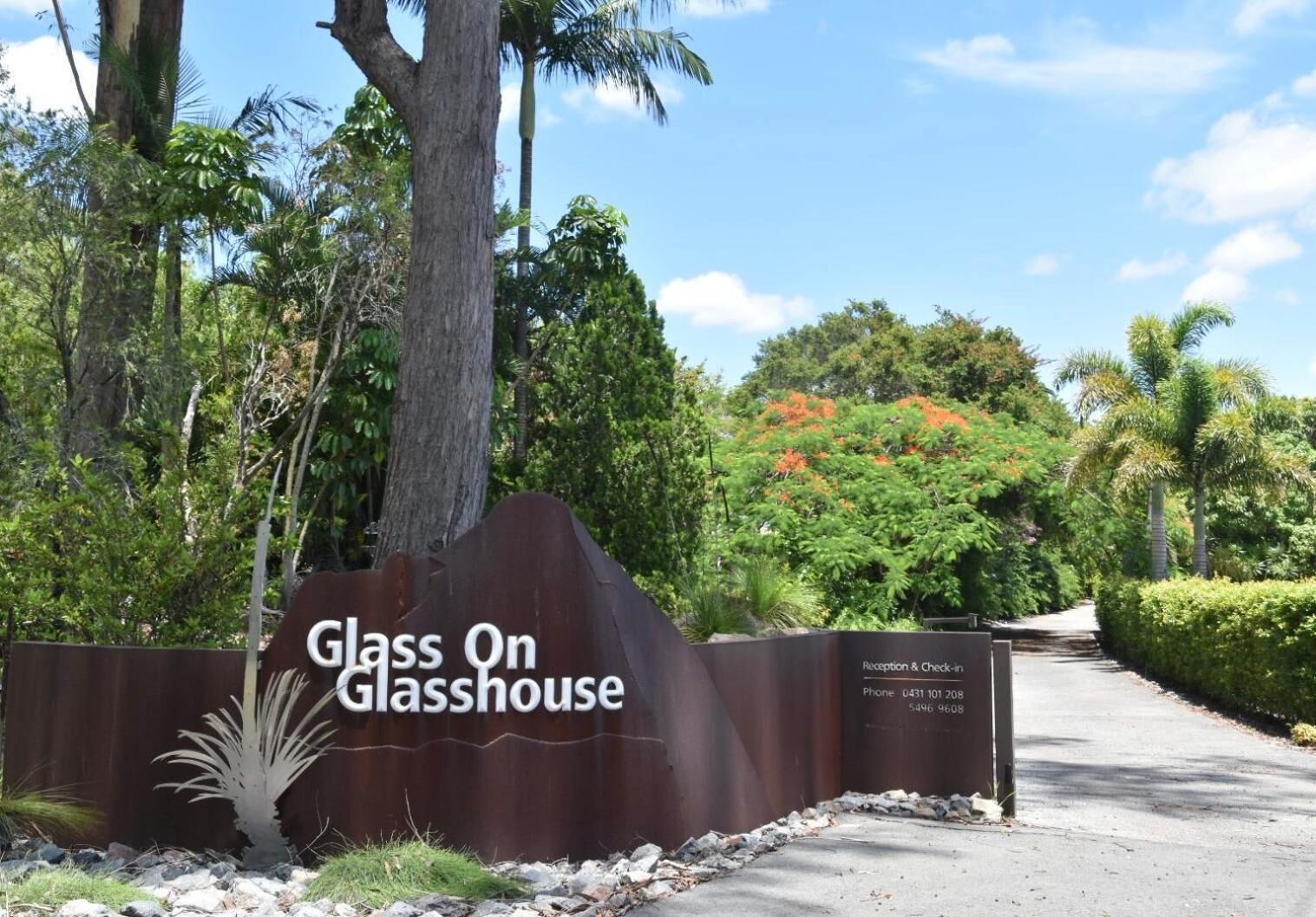 A sign for 'Glass On Glasshouse' with reception and check-in details.
