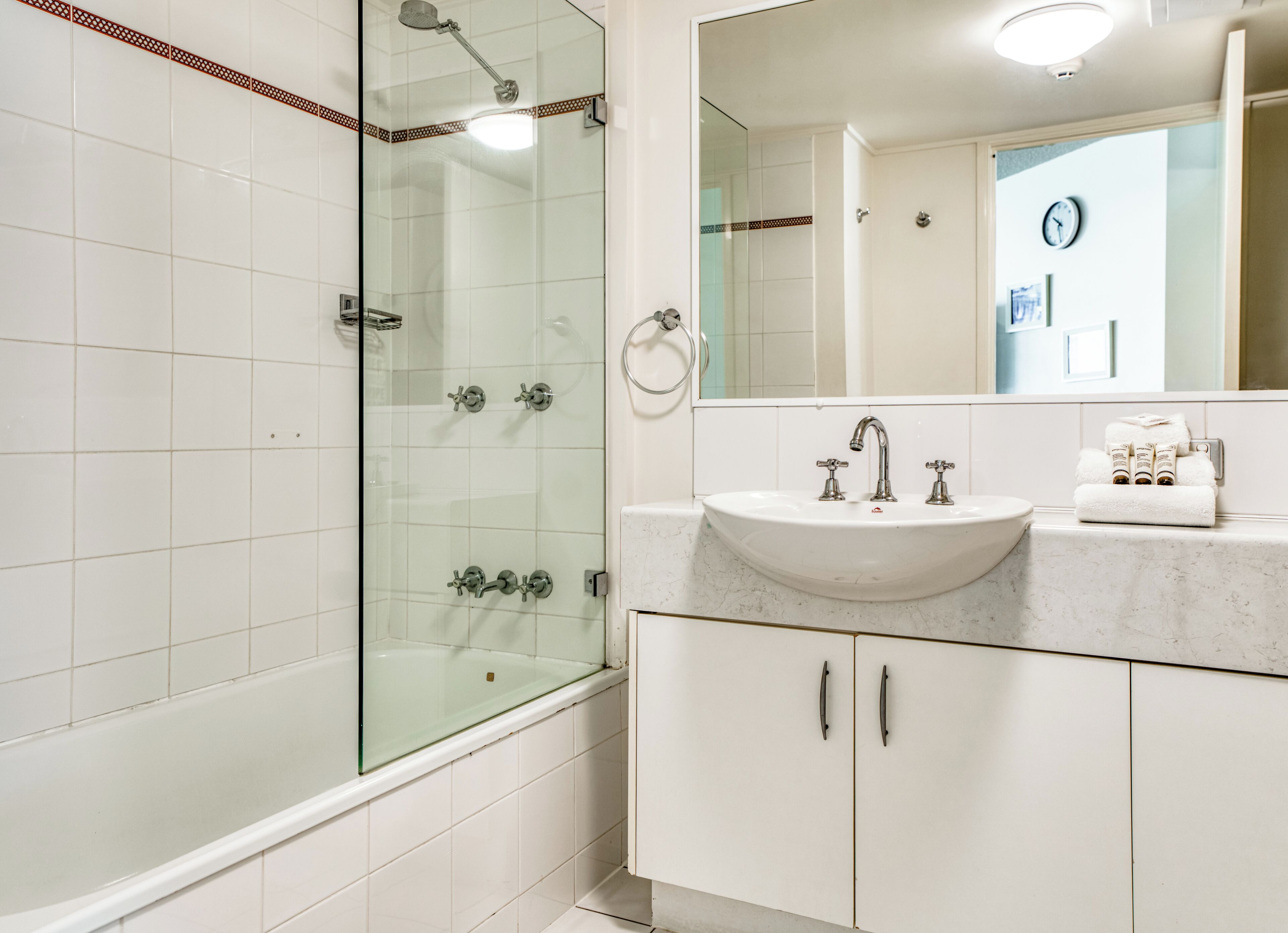 Een moderne badkamer met een douchecabine van glas, een wit wastafelmeubel en een grote spiegel.