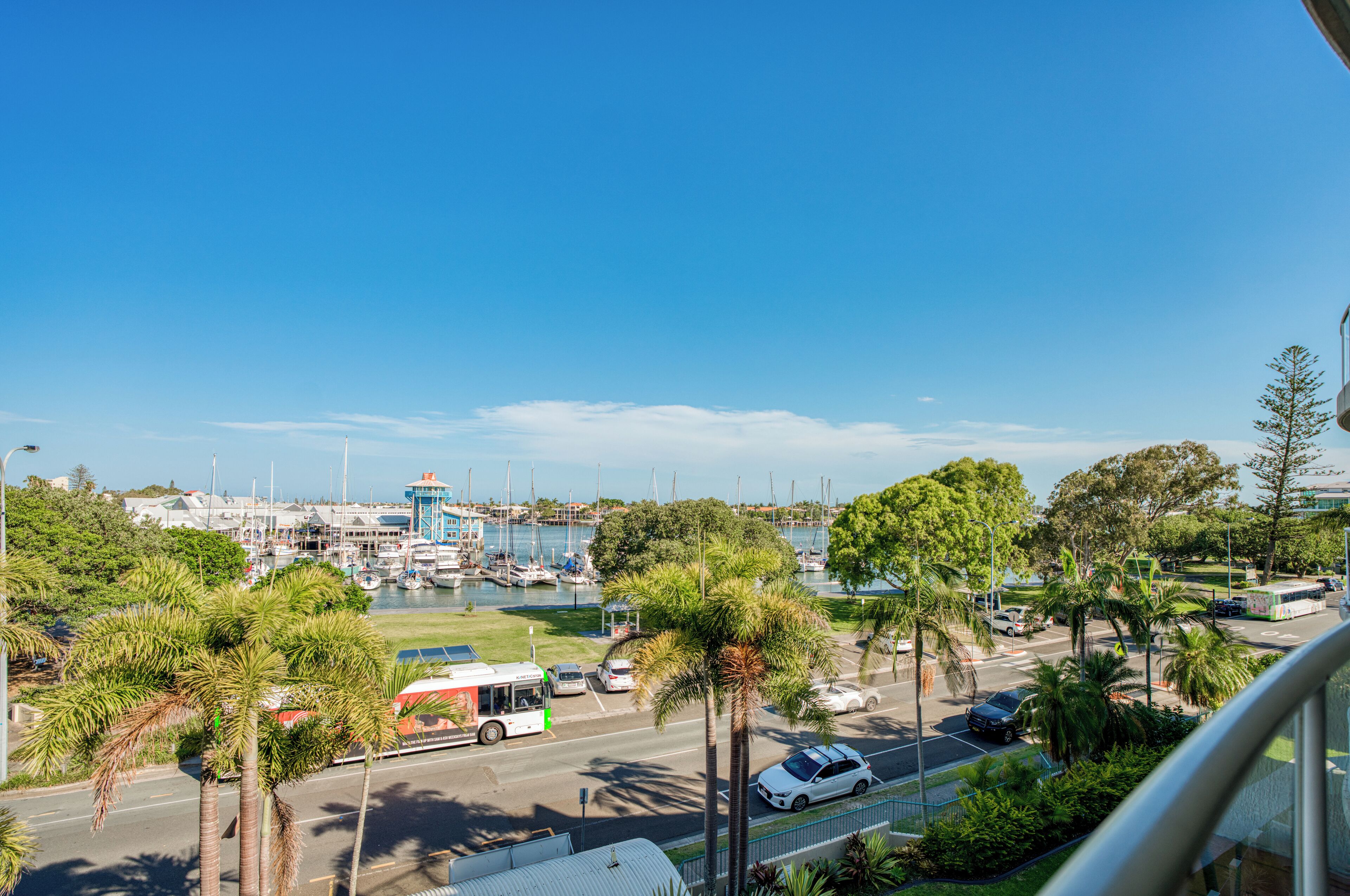 Un puerto deportivo con barcos, un autobús y palmeras.