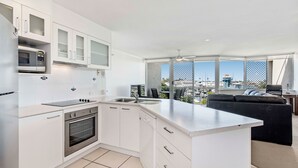 A modern kitchen with white cabinetry, a built-in oven, and a large island.