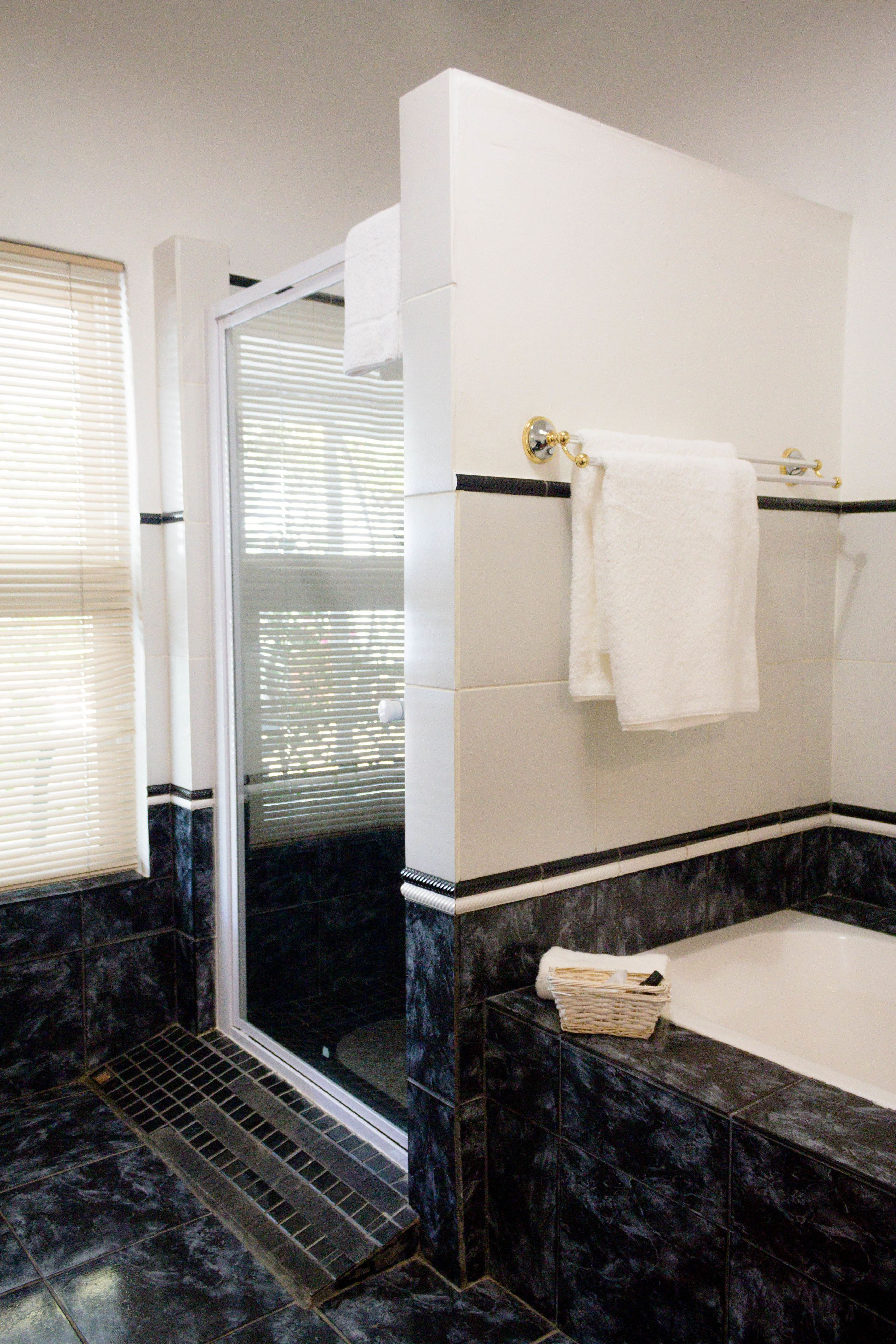 A bathroom with a shower, a bathtub, and a towel rack.