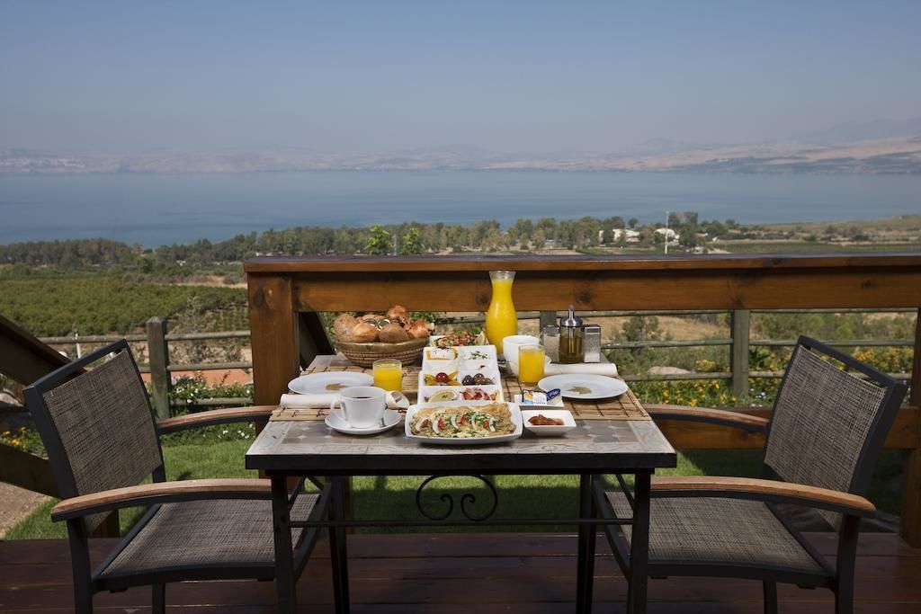 A breakfast table set on a deck with a scenic view of a lake and hills.