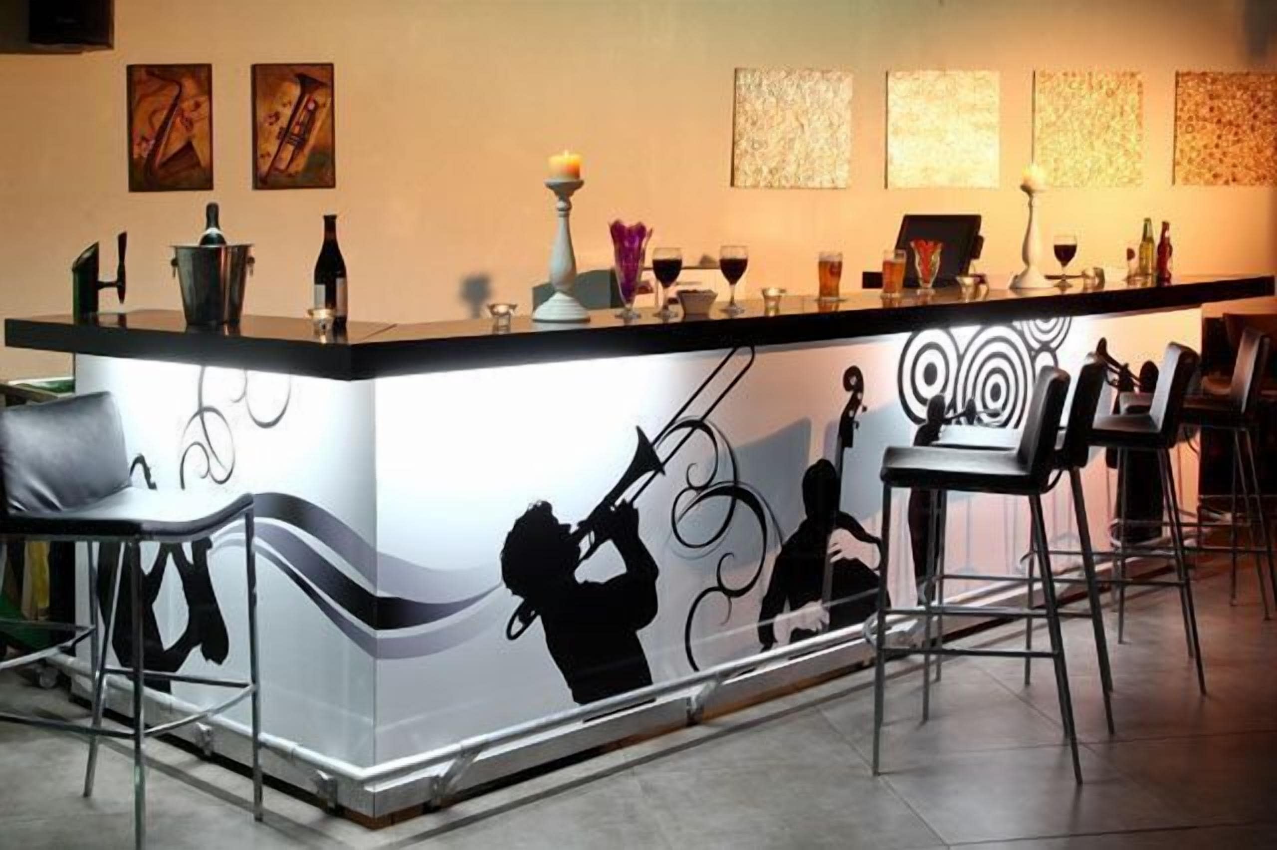 Zona de bar con mostrador, taburetes y una pared con arte abstracto.