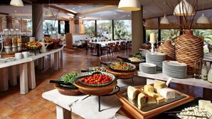 A buffet setup with various food items and a dining area with tables and chairs. - Ramot Resort Hotel (Ramot)