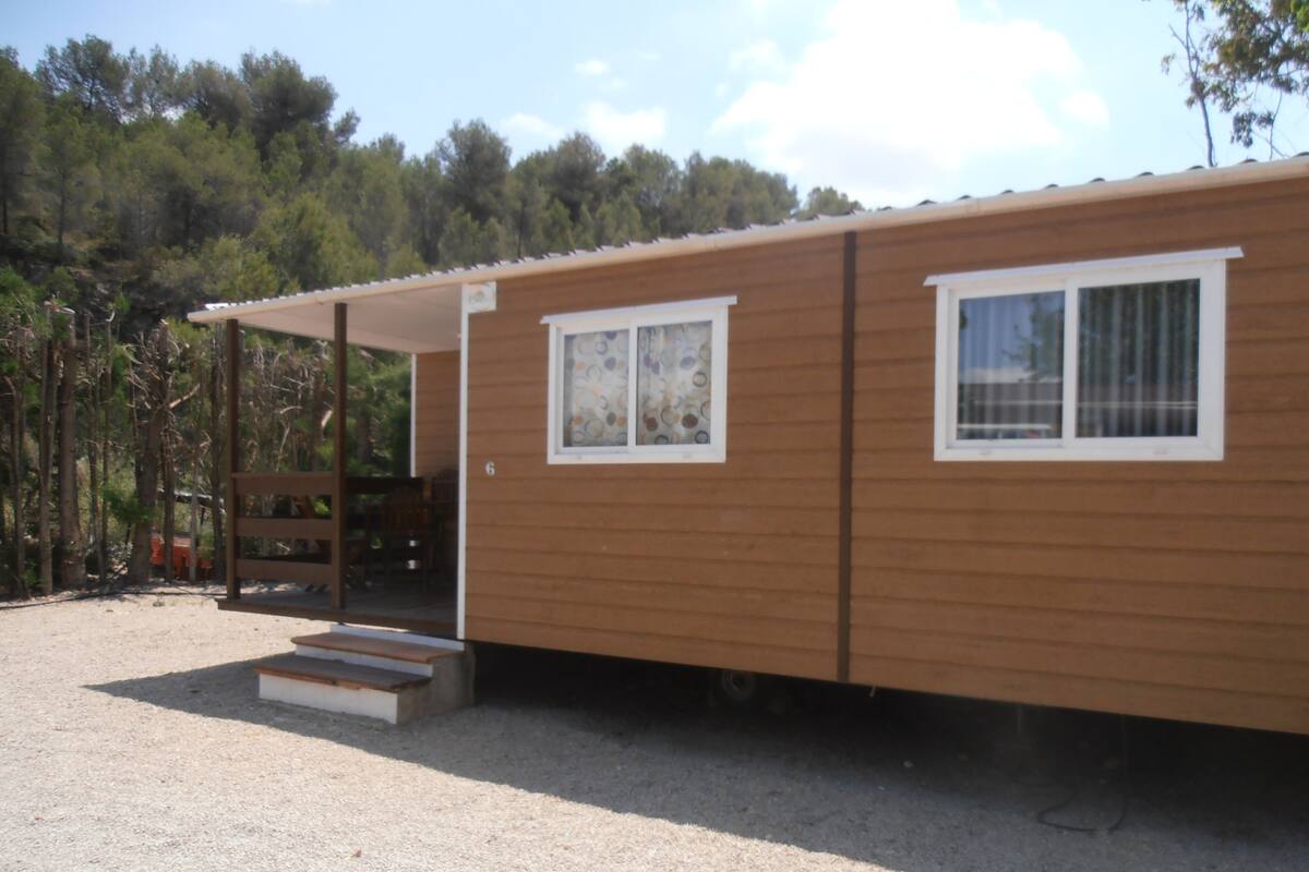 A single-story wooden cabin with a covered porch and a small set of steps leading to the entrance.