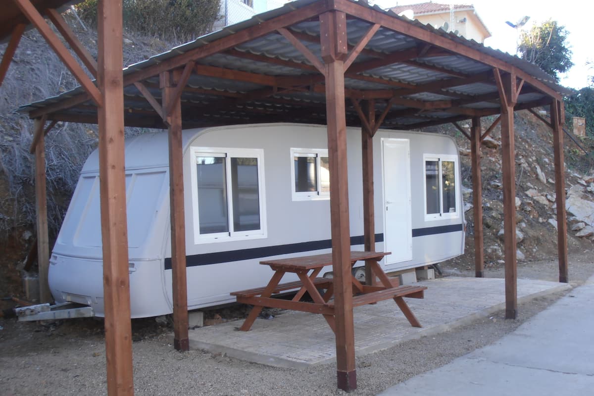 A mobile home with a covered porch and picnic table.