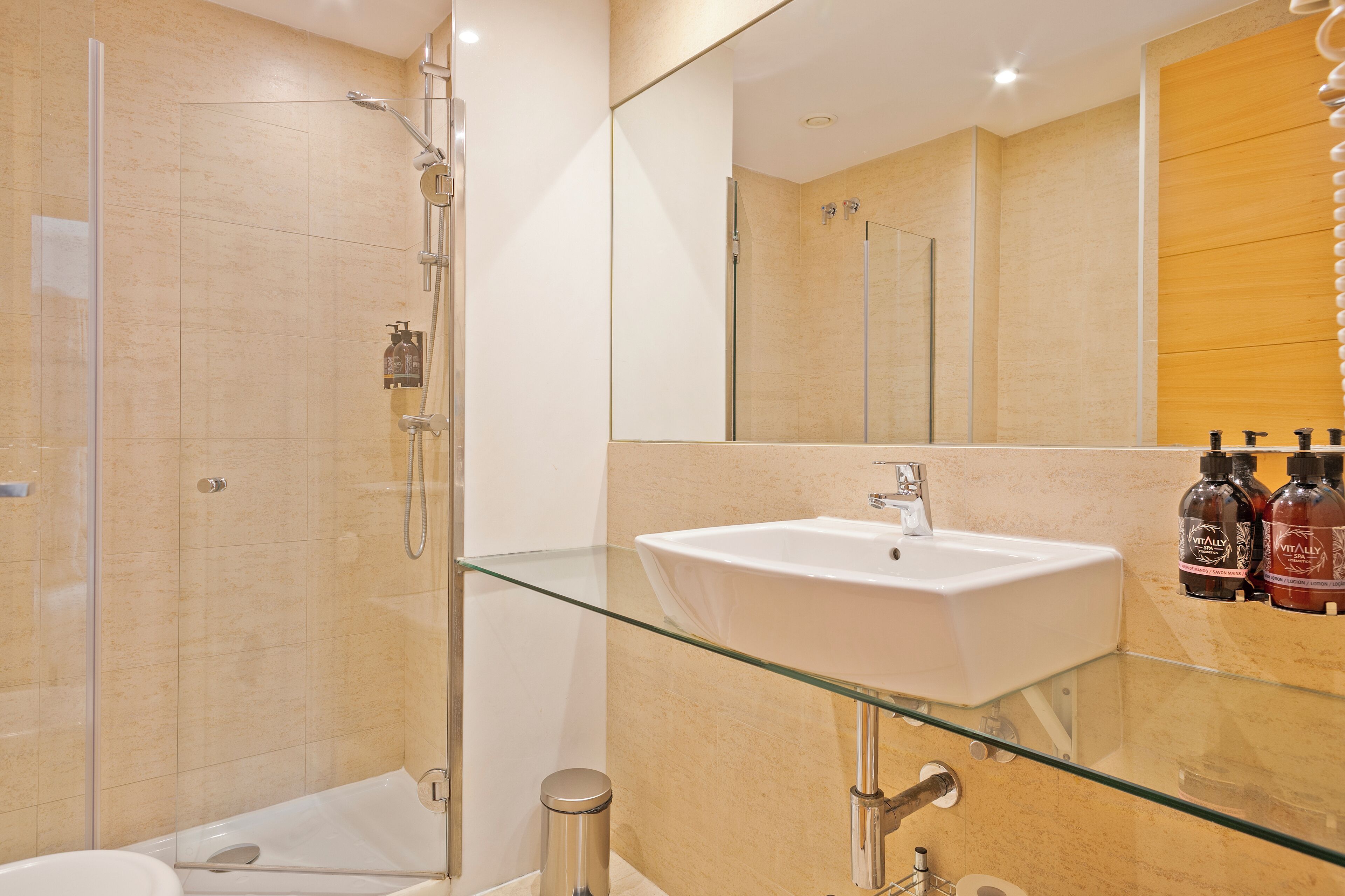 A modern bathroom with a glass shower enclosure, a white sink, and a mirror above it.