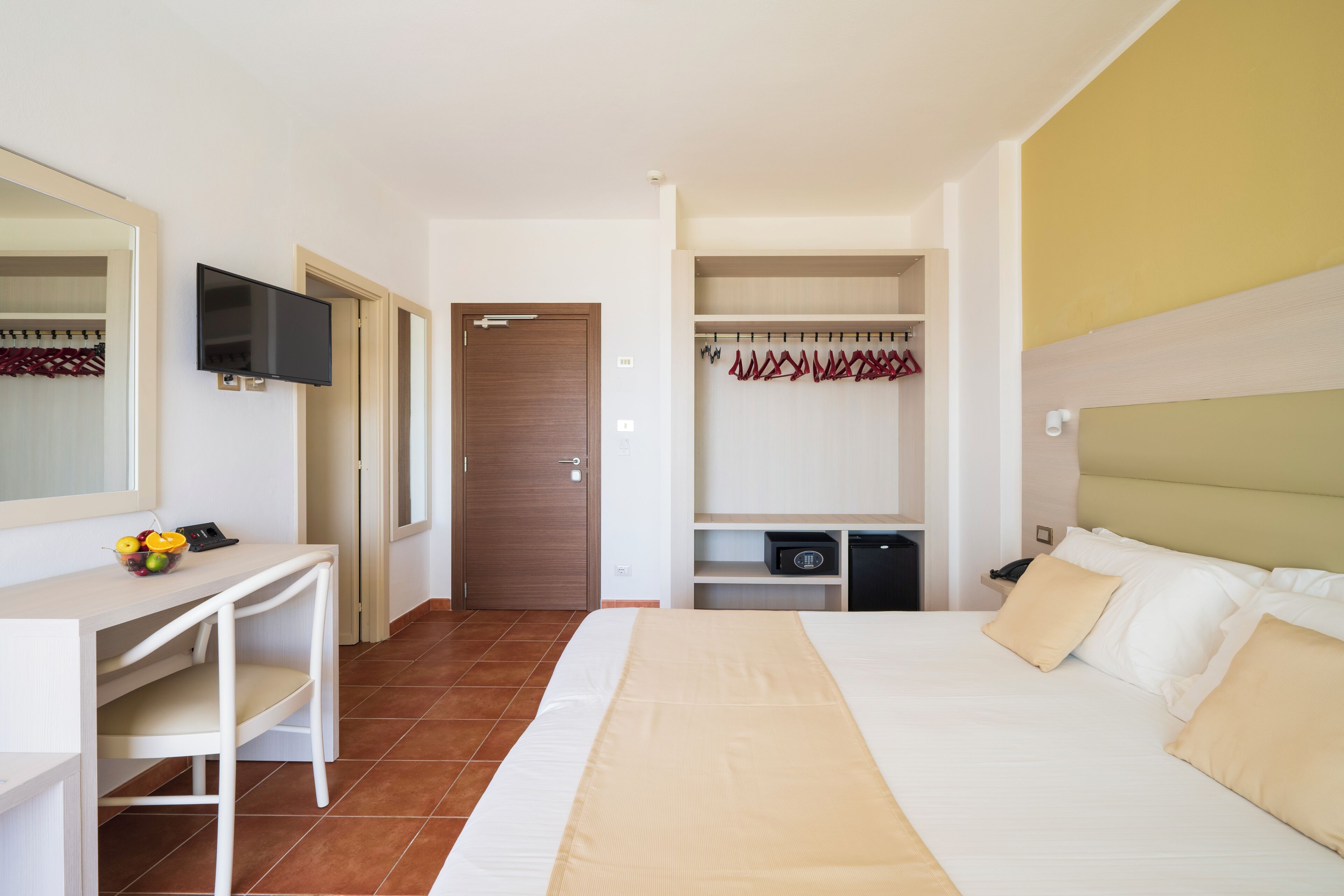 A hotel room with a bed, a desk, a TV, a wardrobe, and a bathroom.