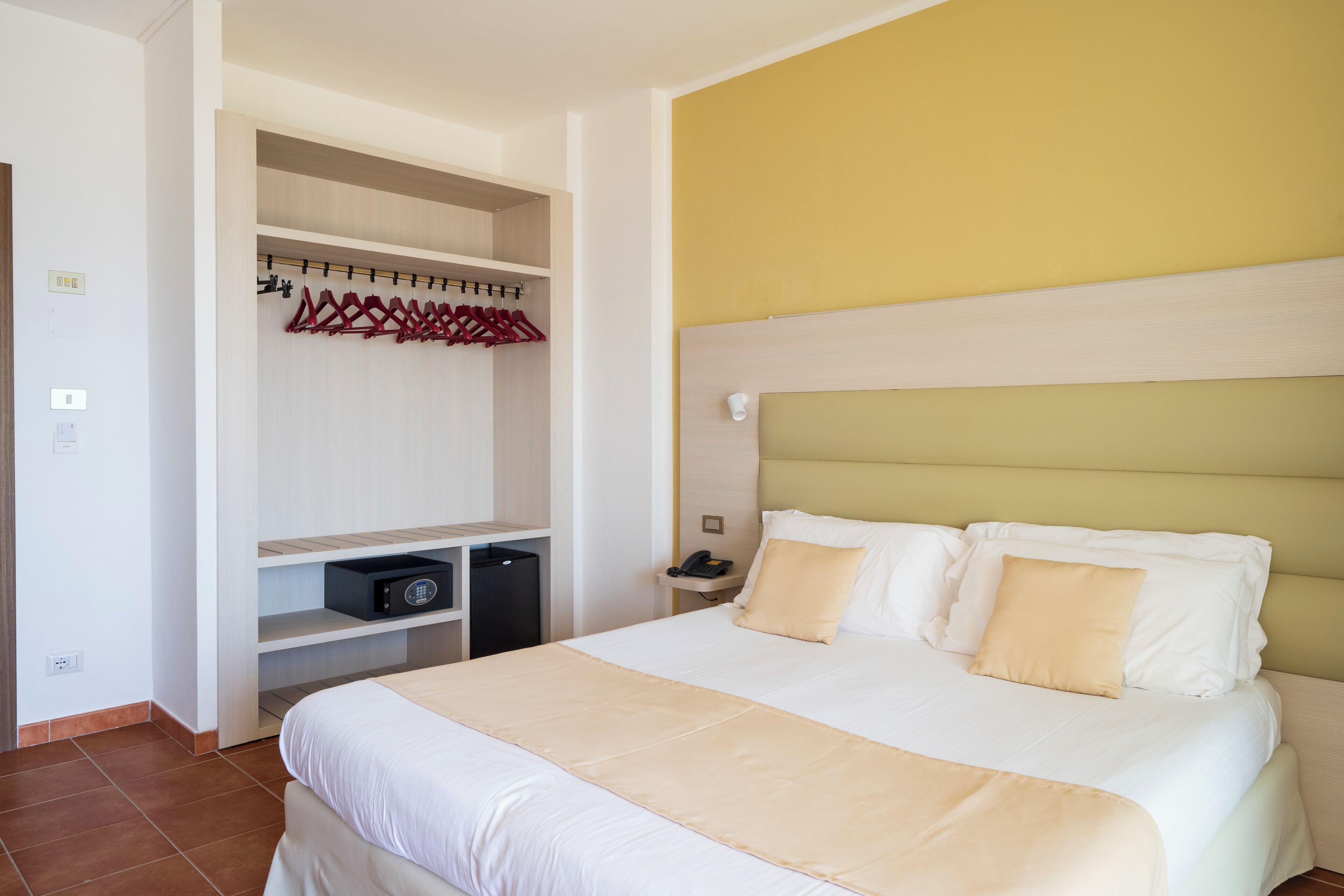 Una habitación de hotel con una cama, un armario y una mesita de noche.