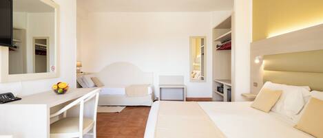 Habitación de hotel con cama, escritorio, silla, televisor y espejo.