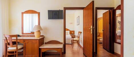 A hotel room with a bed, desk, chair, and a bathroom visible through an open door.