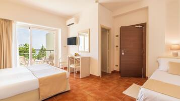 Camera d'albergo con due letti, una scrivania, una TV e un balcone con mobili da esterno.