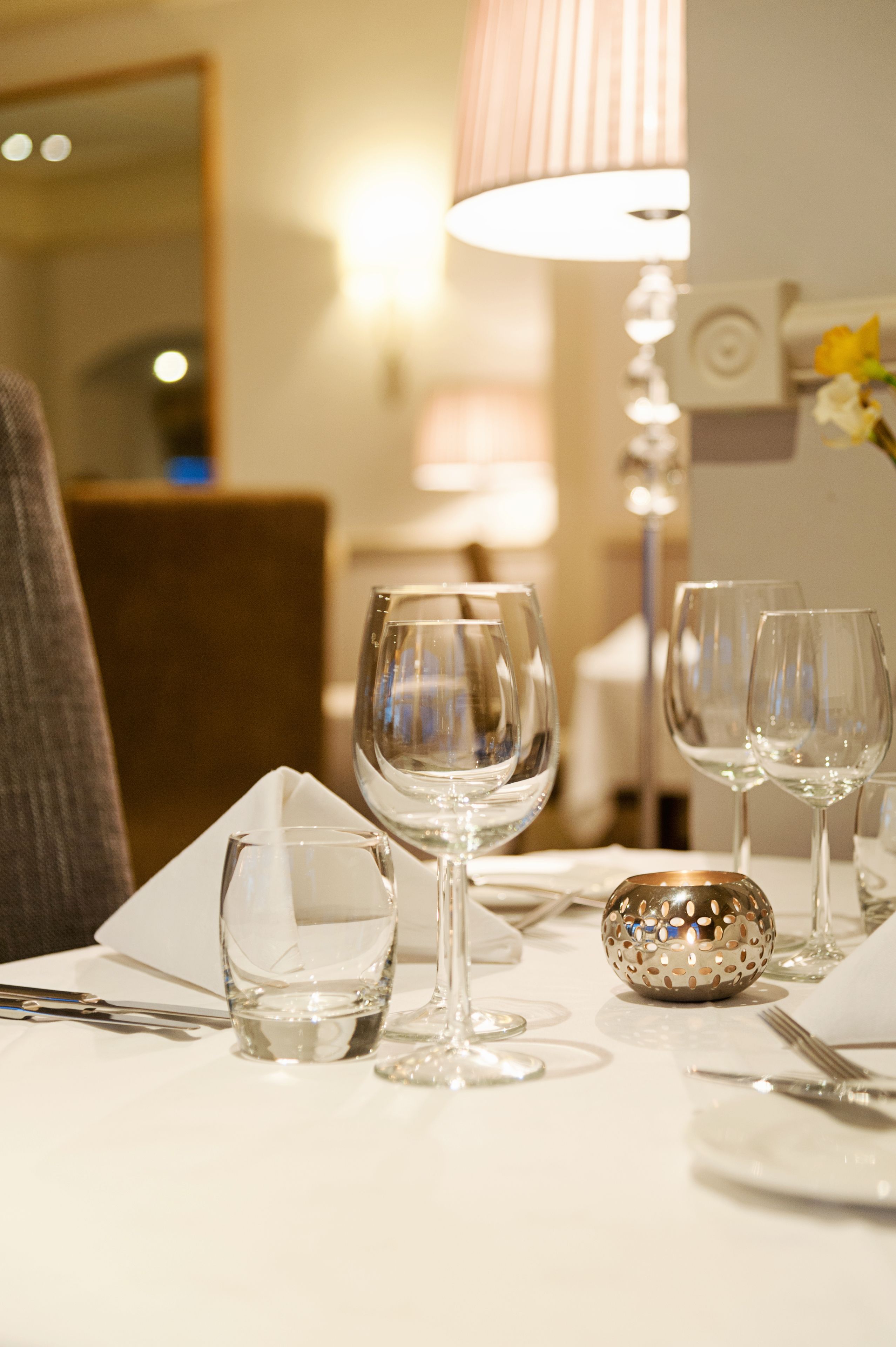 Une table à manger dressée avec des verres à vin, un petit bol décoratif et des couverts.