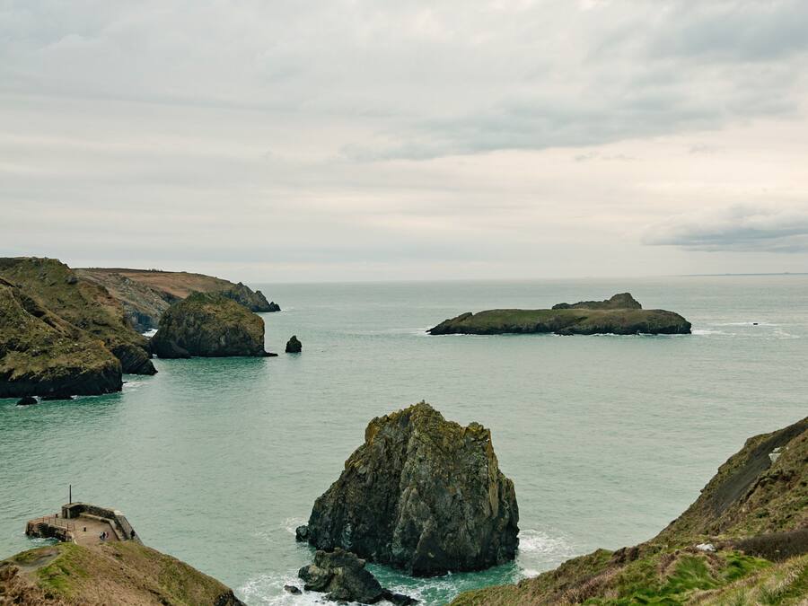 A coastal landscape with rocky outcrops and a small building near the water.