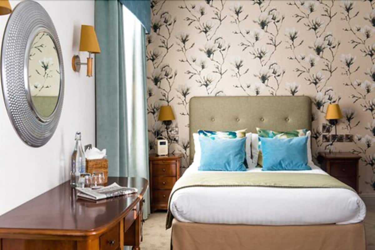 A bedroom with a bed, two bedside tables, a mirror, and a dresser.