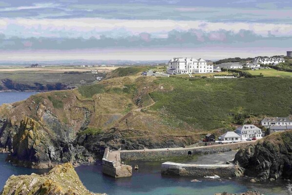 A coastal property with a large house, a fortified structure, and a view of the sea.