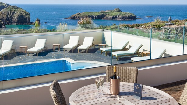 A rooftop pool area with lounge chairs and a table with champagne glasses and a bottle.