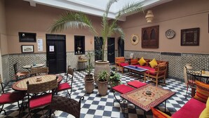 A traditional interior with checkered flooring, a central seating area with a sofa and chairs, and a small table with a decorative item. - Riad Sidi Magdoul (Essaouira)