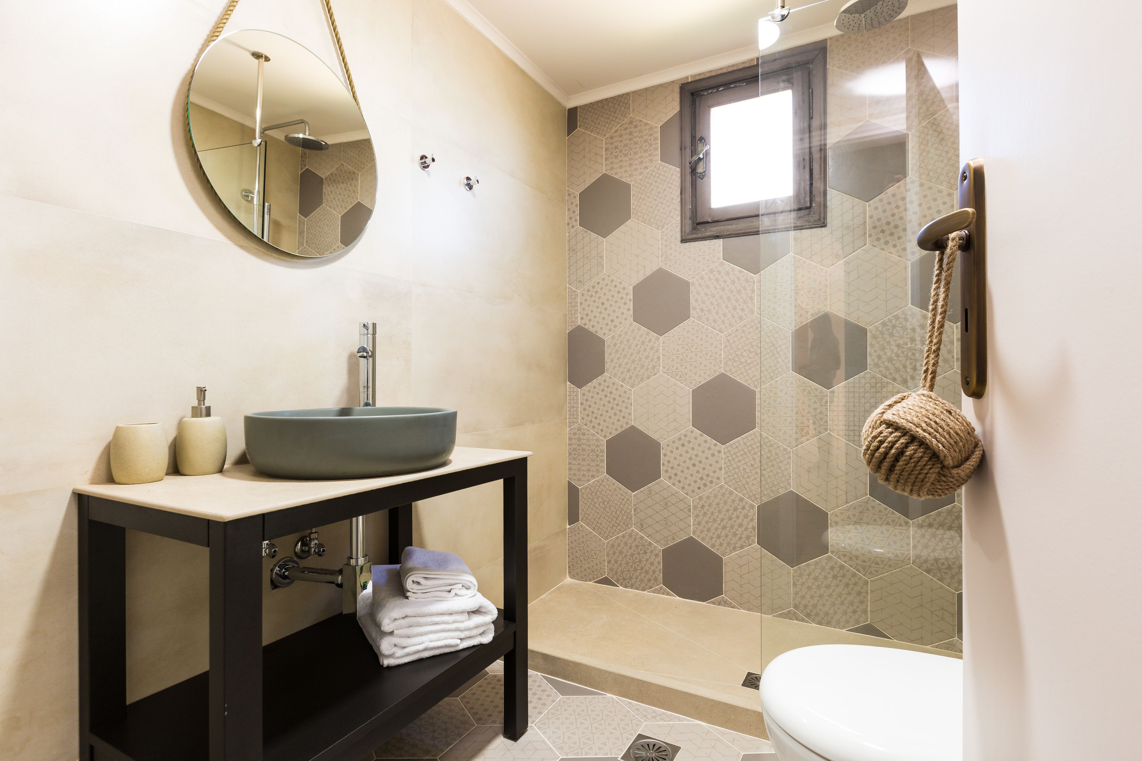 Un baño moderno con un espejo redondo, un lavabo, un inodoro y una zona de ducha.