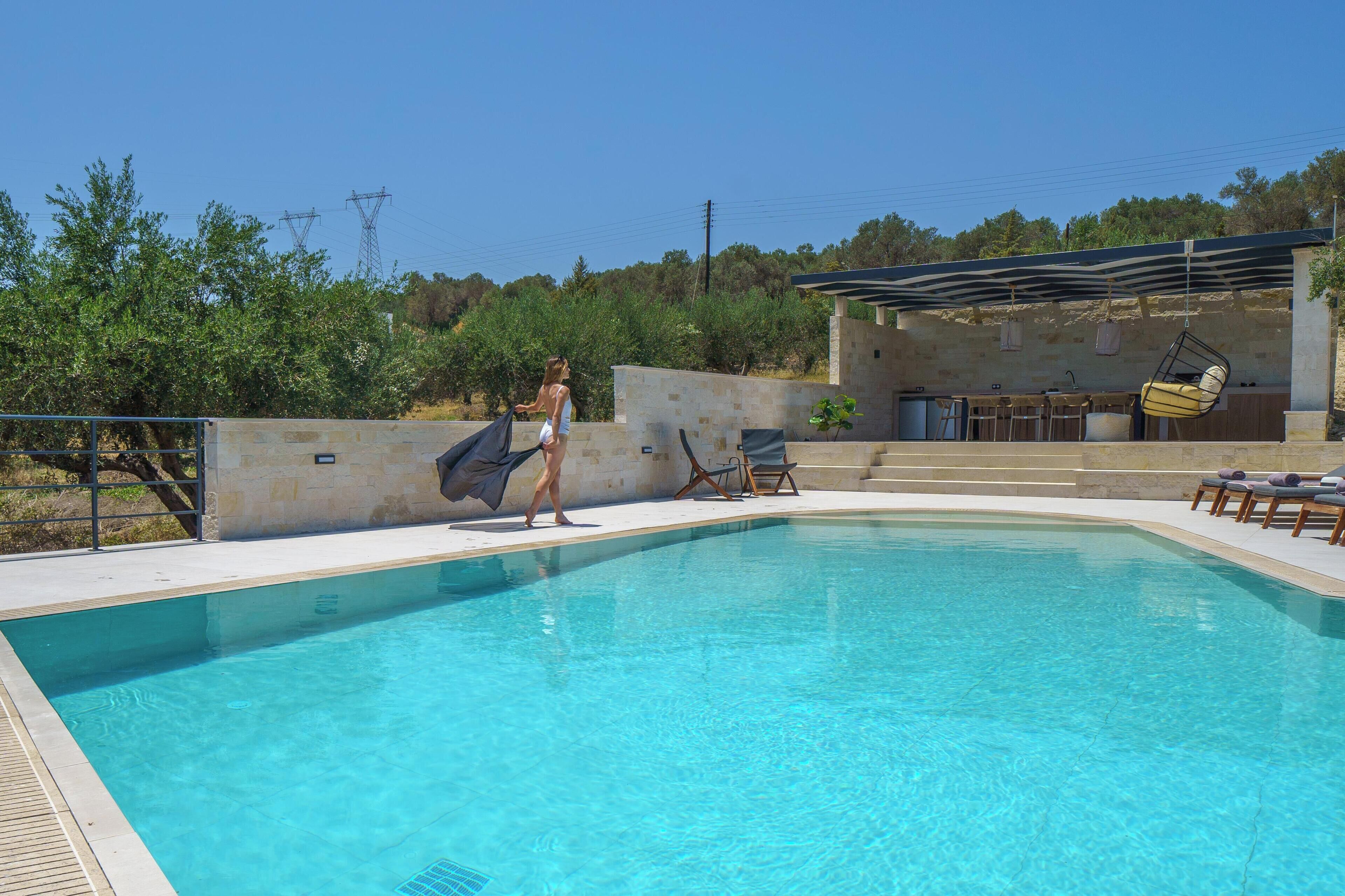 A swimming pool with lounge chairs and a covered area.