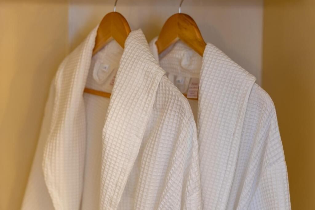 Dos batas blancas colgadas en perchas de madera.