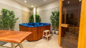 Un área de spa con un jacuzzi de madera, una camilla de masaje y plantas en macetas.